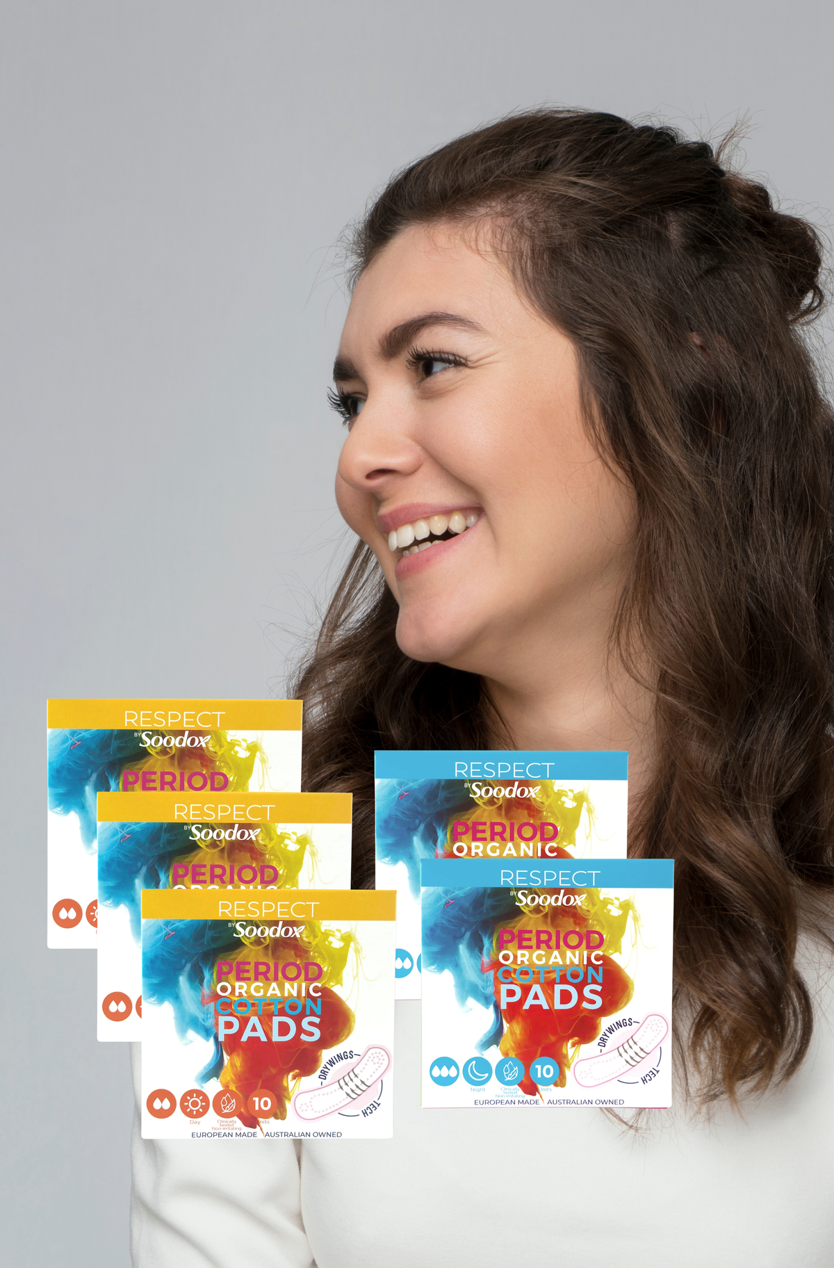 Smiling woman beside Soodox organic cotton day and night pad boxes